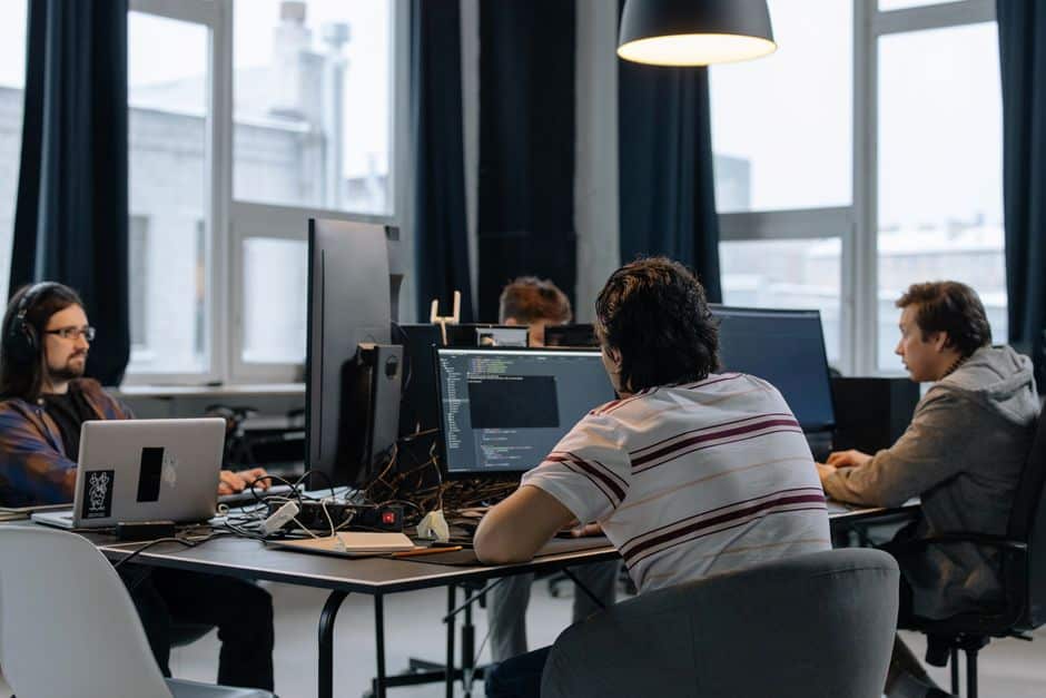 Développeurs concentrés sur leurs écrans dans un bureau tech moderne